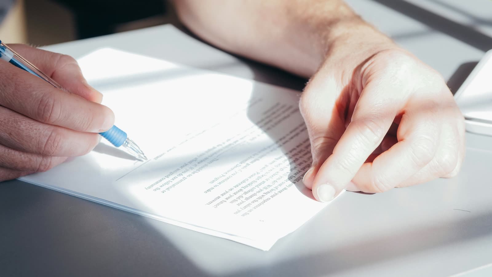 Hands preparing to sign a document in bright light