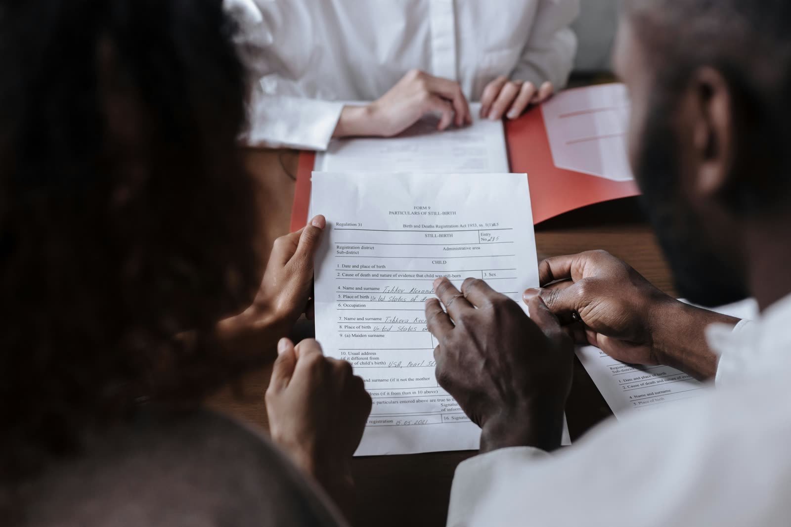 Advisor guiding clients through document signing at a table