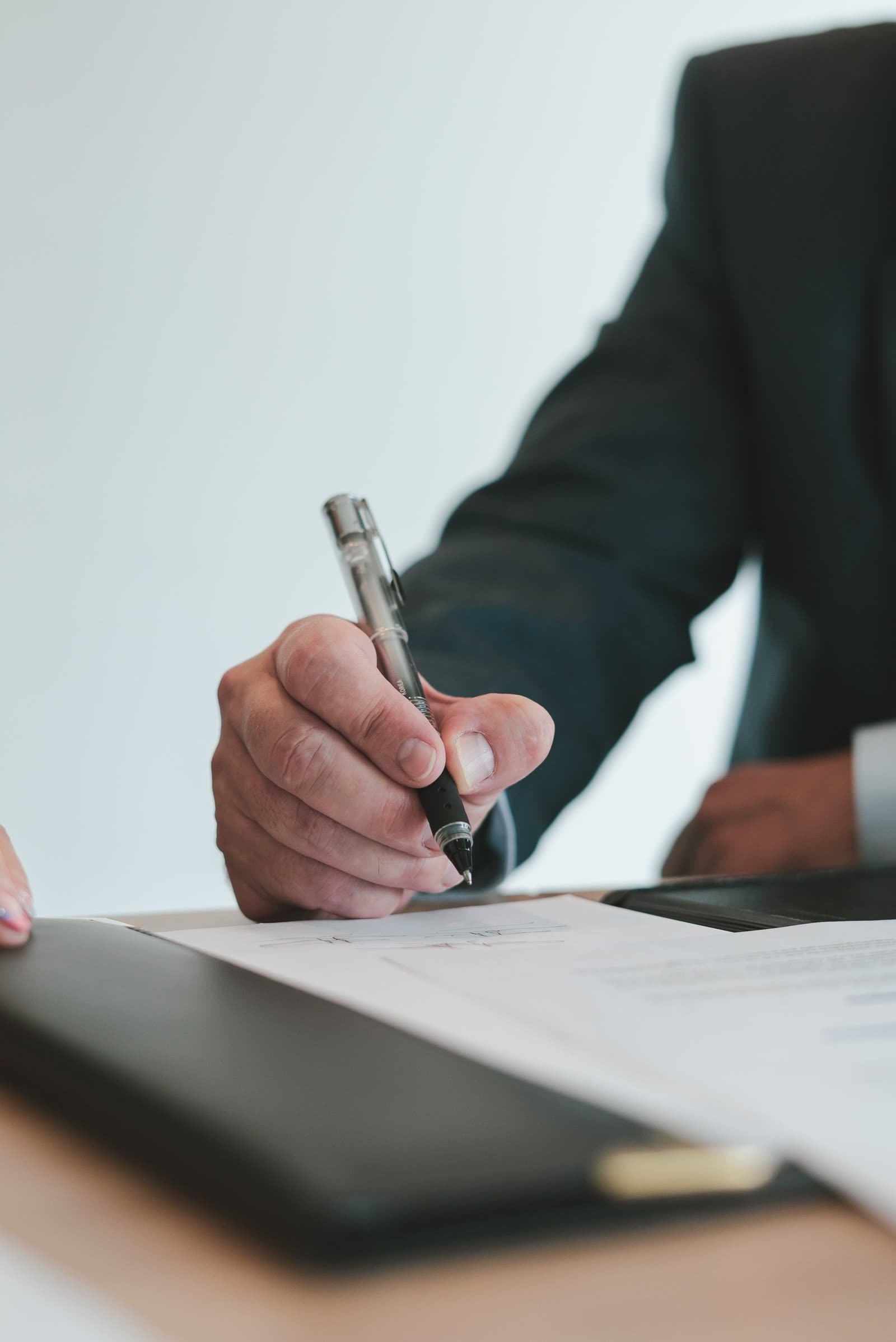 Professional hand holding a pen over documents at a desk