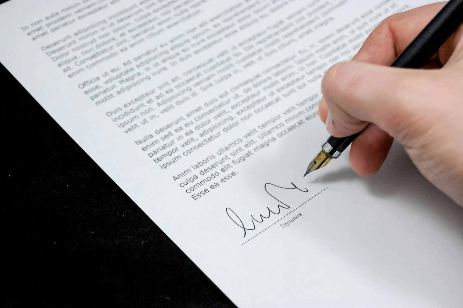 Close-up of a hand signing a formal document with a fountain pen